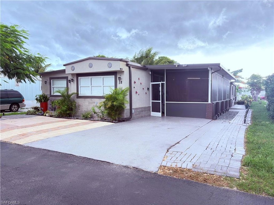 View of front of house with a sunroom, driveway, and stucco siding
