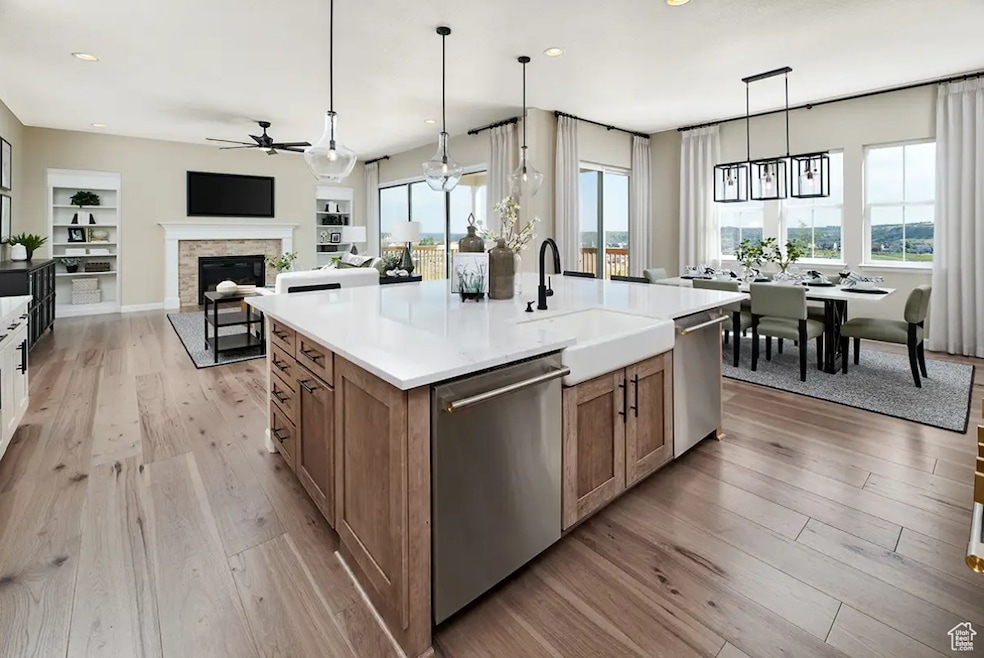 Kitchen featuring stainless steel dishwasher, a ceiling fan, brown cabinetry, light wood finished floors, and recessed lighting