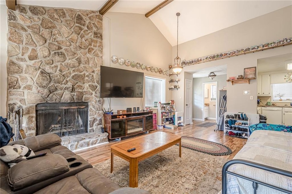 Living area featuring beam ceiling, a healthy amount of sunlight, and light wood-style flooring