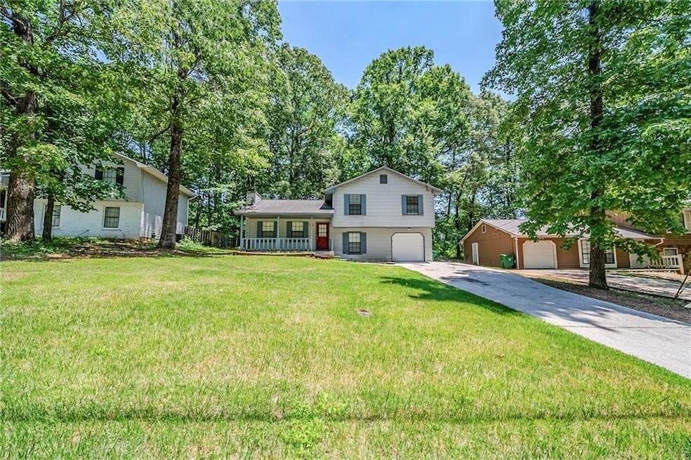 Split level home with a porch, a front lawn, an attached garage, and driveway