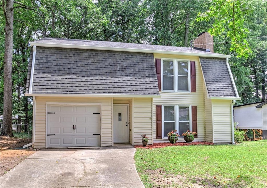 Colonial inspired home with roof with shingles, a chimney, driveway, and a front lawn