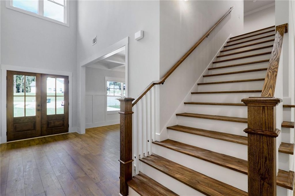 Entryway with french doors, hardwood / wood-style flooring, a high ceiling, a decorative wall, and wainscoting