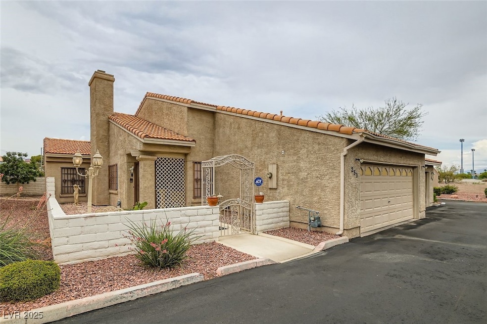 Mediterranean / spanish home with a tiled roof, an attached garage, stucco siding, and a chimney