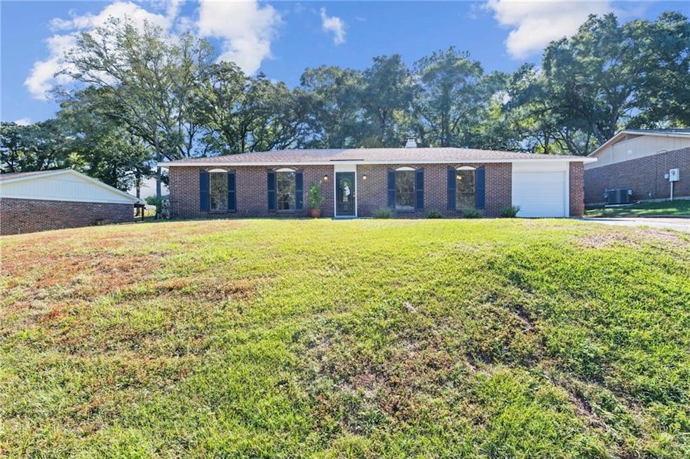 Ranch-style home featuring brick siding, a front yard, and a garage