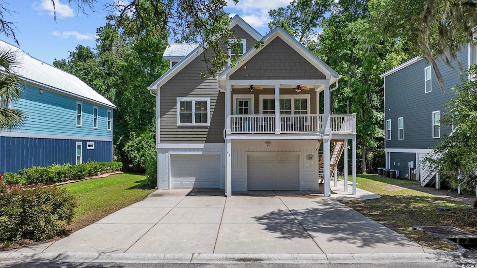 Beach home with ceiling fan, stairs, a front lawn, concrete driveway, and a garage