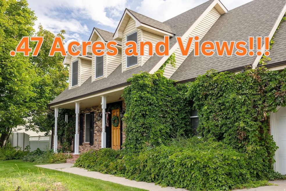 View of front facade with roof with shingles, covered porch, brick siding, a front yard, and a garage