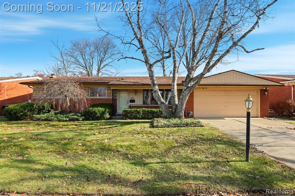 View of front of house with brick siding, driveway, a front lawn, covered porch, and a garage