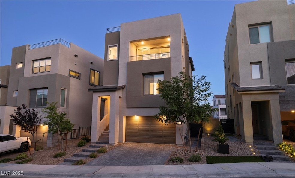 Contemporary home featuring a garage, decorative driveway, stucco siding, and a balcony
