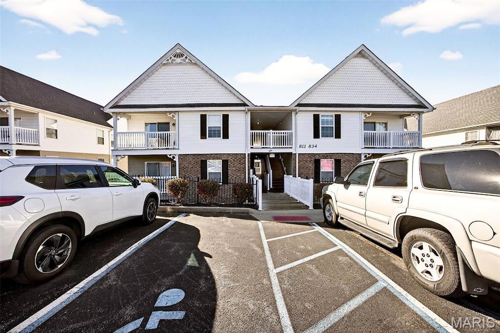View of front of home featuring stairway, brick siding, and uncovered parking