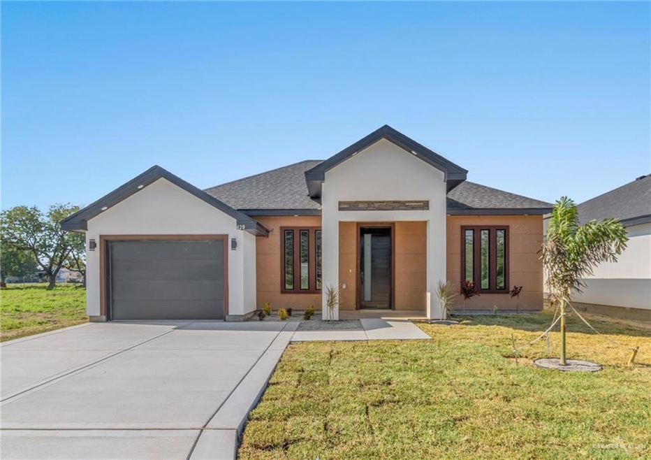 View of front facade featuring a garage, a front lawn, and french doors