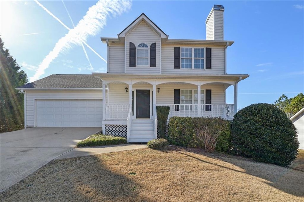 Traditional-style home featuring a chimney, concrete driveway, an attached garage, and covered porch
