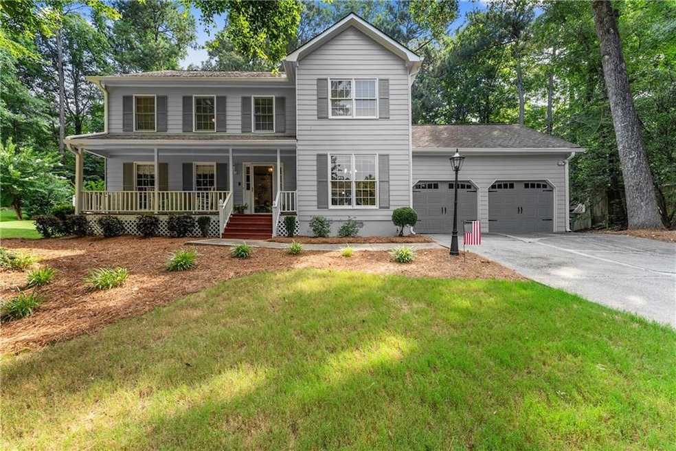 View of front of property featuring an attached garage, a porch, concrete driveway, and a front yard