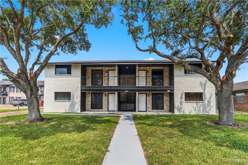 Townhome / multi-family property featuring brick siding, a front lawn, and a balcony