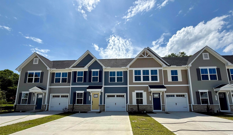 Multi unit property with driveway, stone siding, a garage, and board and batten siding