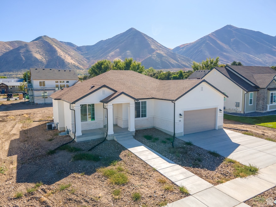 Ranch-style home featuring concrete driveway, brick siding, a garage, and a mountain view