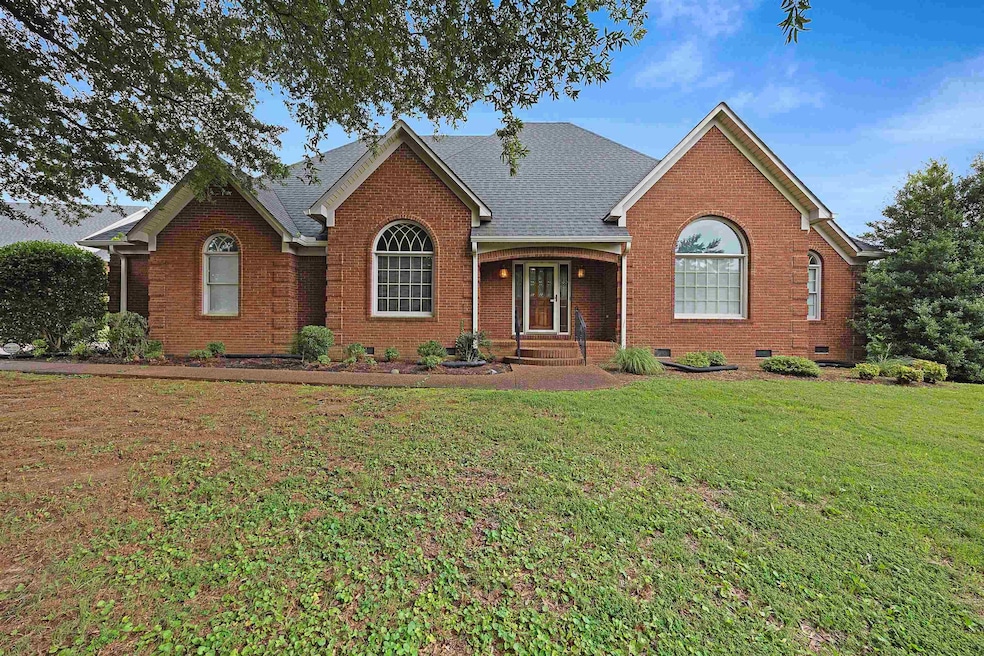 View of front of property with brick siding, a front lawn, a shingled roof, and crawl space