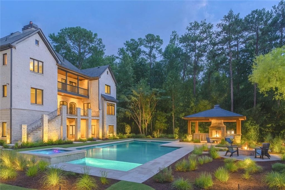 View of swimming pool featuring a gazebo, a patio area, a pool with connected hot tub, a lit fireplace, and stairway
