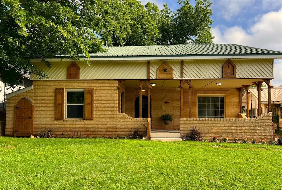 View of front of property with a porch, brick siding, and a front yard