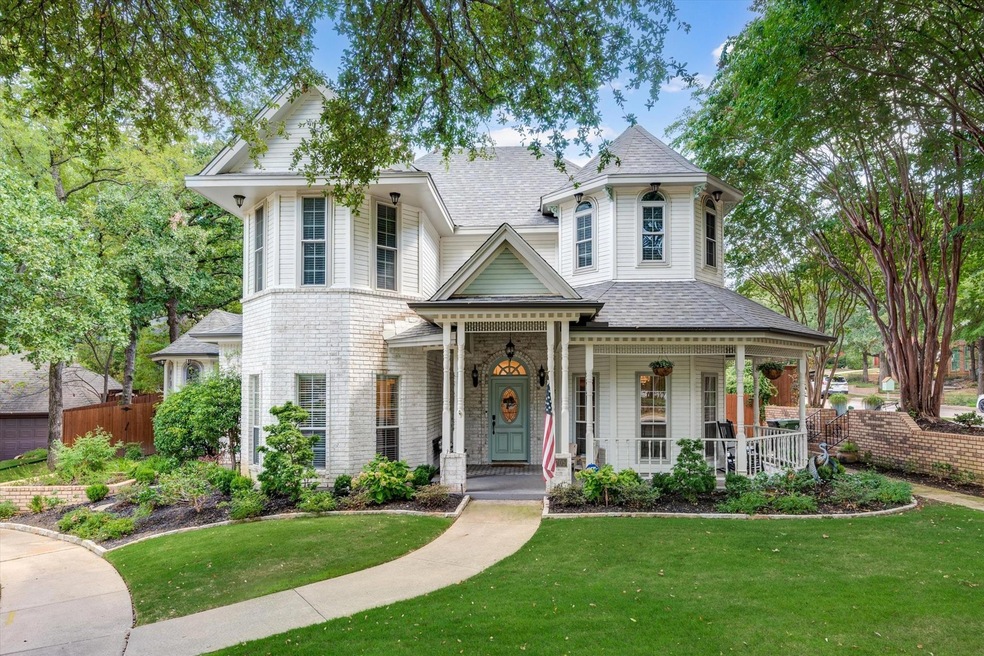 Victorian-style home featuring covered porch and full flower bed landscaping