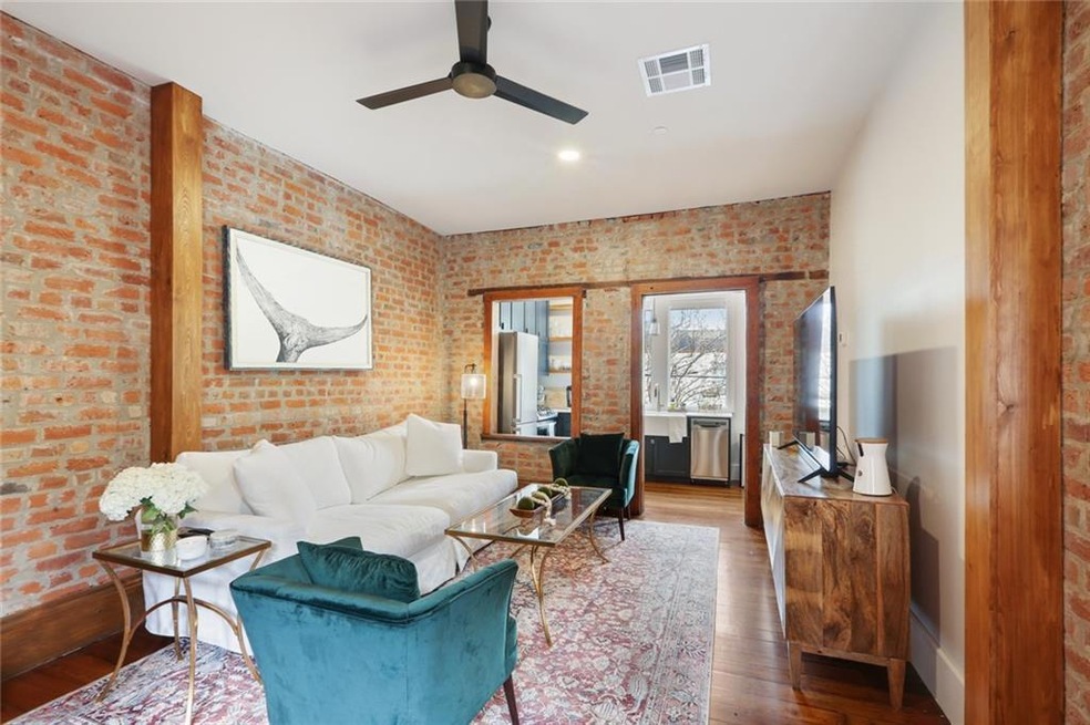 Living area with gorgeous exposed beams and brick, in addition to beautiful hardwood floors and tall ceilings.