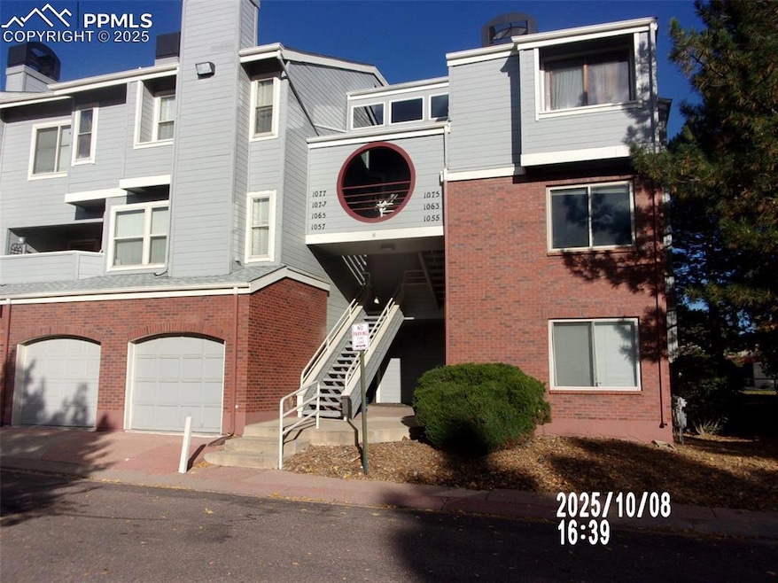 View of property featuring stairs, a garage, and driveway