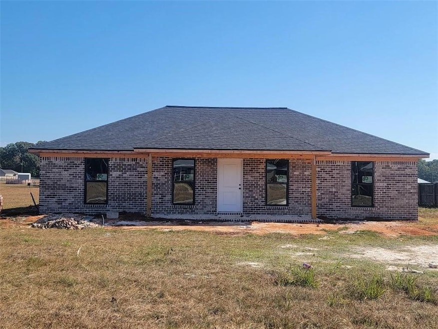 View of front of home featuring brick siding, a front yard, and roof with shingles