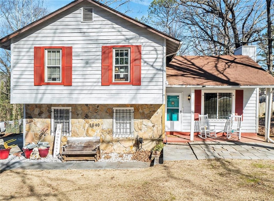 View of front of home with stone siding, a porch, and a chimney