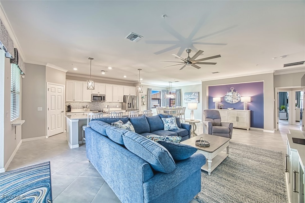 Living area with ornamental molding, light tile patterned flooring, a ceiling fan, and recessed lighting