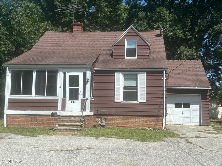 Cape cod house featuring a garage and an outbuilding