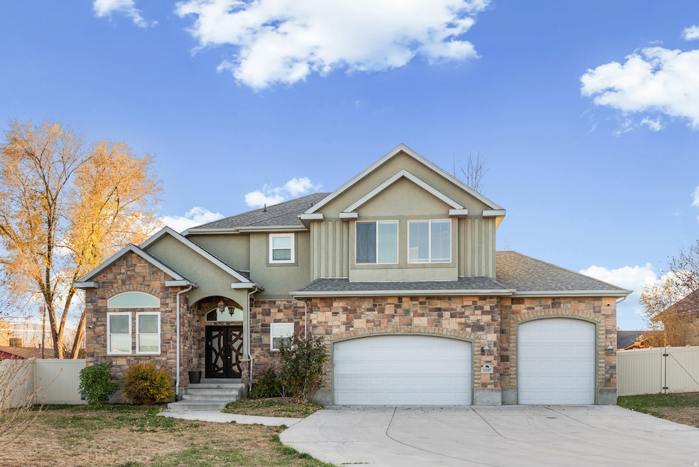 View of front of home with stone siding, an attached garage, a gate, driveway, and roof with shingles