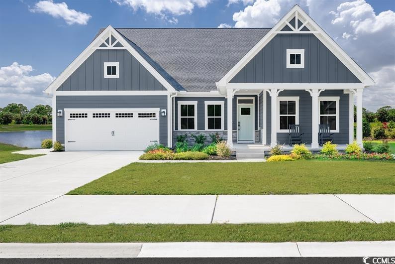 View of front of house featuring board and batten siding, a porch, a front yard, a garage, and driveway