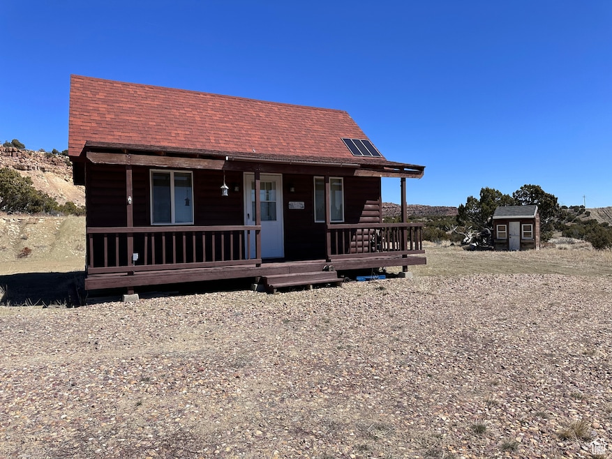 View of front of home with a porch, solar panels, and a shed