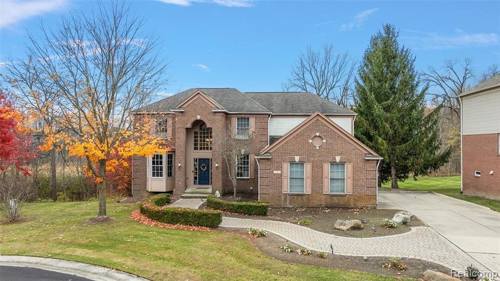 View of front of home featuring a front lawn, brick siding, driveway, and roof with shingles