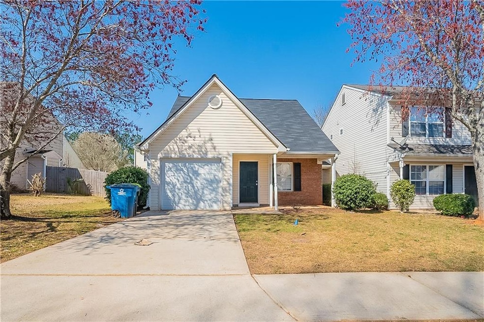Traditional-style home featuring brick siding, a front yard, fence, a garage, and driveway