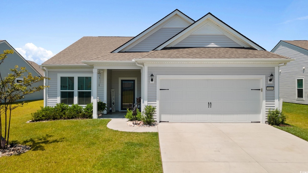 View of front facade featuring a garage, driveway, a shingled roof, and a front yard