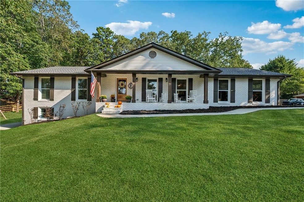 Single story home with a porch, brick siding, and a front lawn