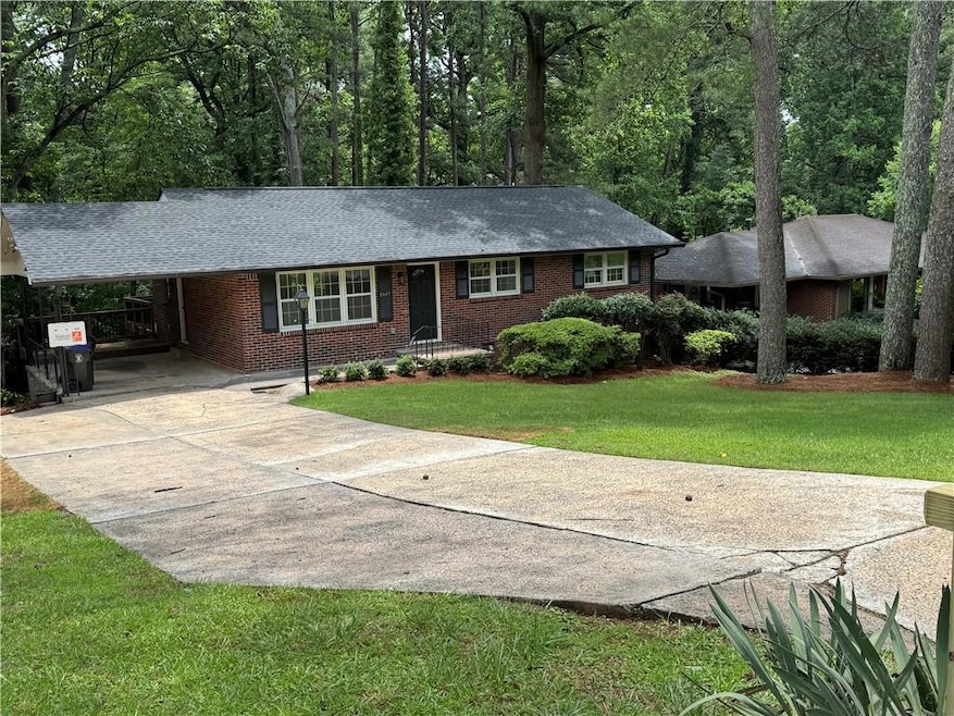 Ranch-style home featuring brick siding, driveway, a front yard, and roof with shingles