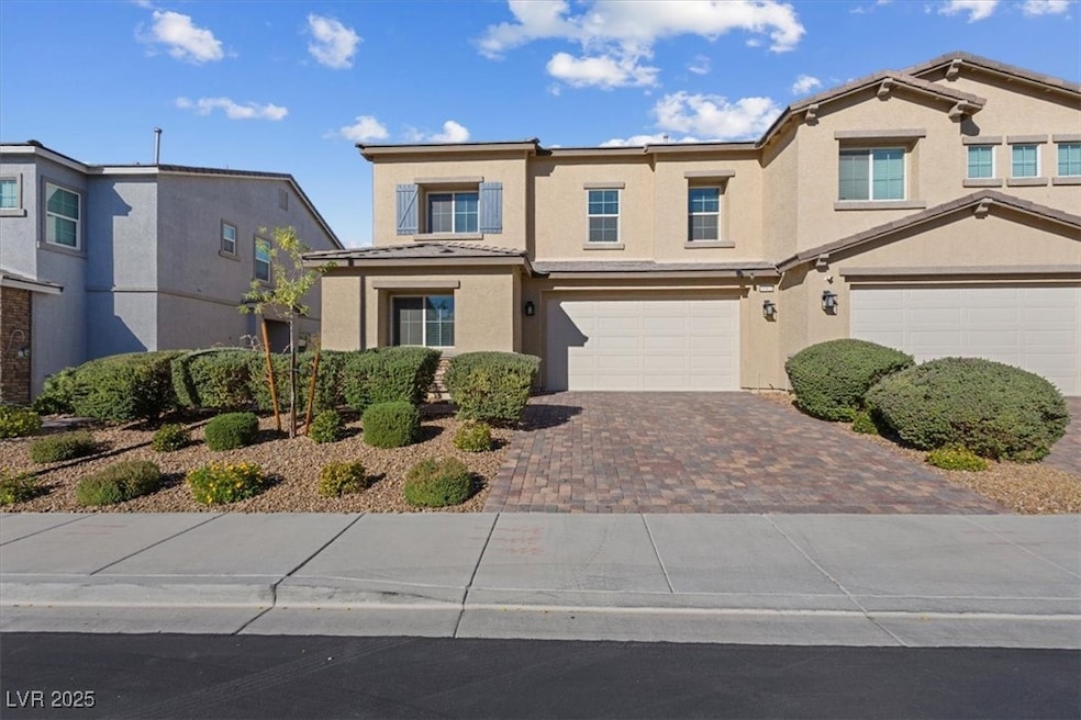 Traditional-style home featuring decorative driveway, stucco siding, and an attached garage