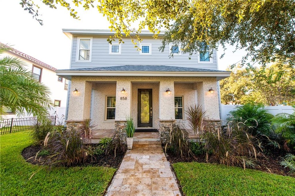 Beautiful facade features travertine tile, stacked stone on the columns, stucco and coquina shell coastal modern design, and fresh new landscaping and sod