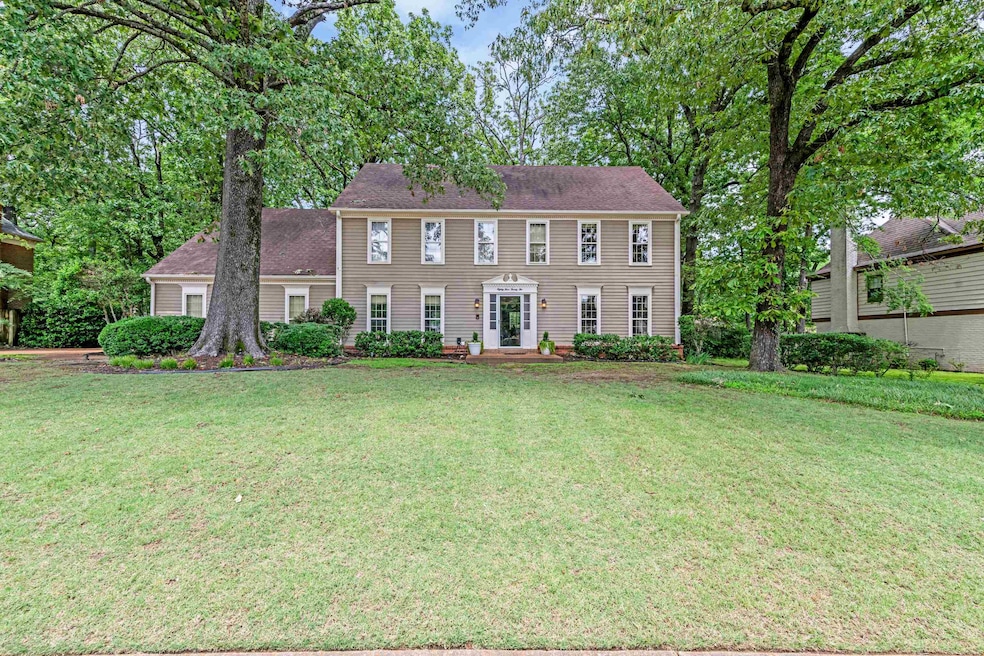 Colonial home with a front lawn and roof with shingles