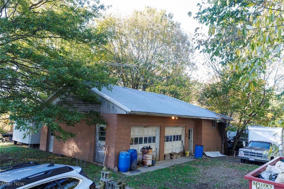 View of side of home with brick siding, an outdoor structure, a metal roof, and a garage