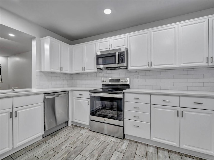 Kitchen featuring appliances with stainless steel finishes, white cabinets, wood finish floors, and recessed lighting