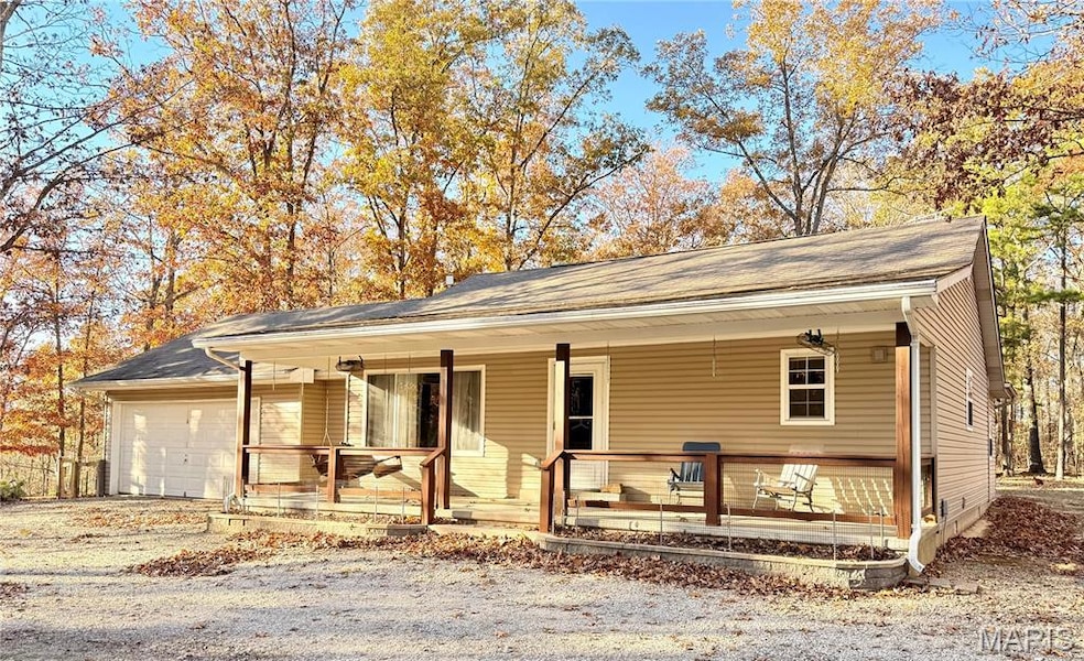 View of front of property with a porch, a garage, and driveway