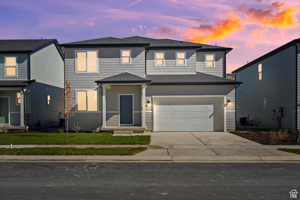 Traditional home with concrete driveway, an attached garage, and roof with shingles