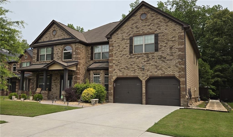 View of front of property featuring driveway, an attached garage, a front lawn, brick siding, and a porch