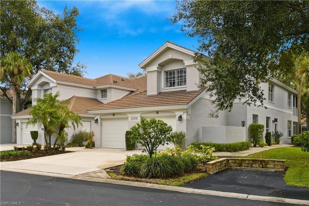 Traditional-style house with a garage, driveway, stucco siding, and a tiled roof