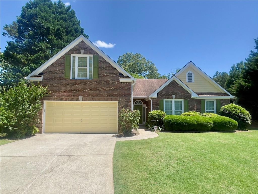 Traditional-style house with brick siding, concrete driveway, a front lawn, and an attached garage
