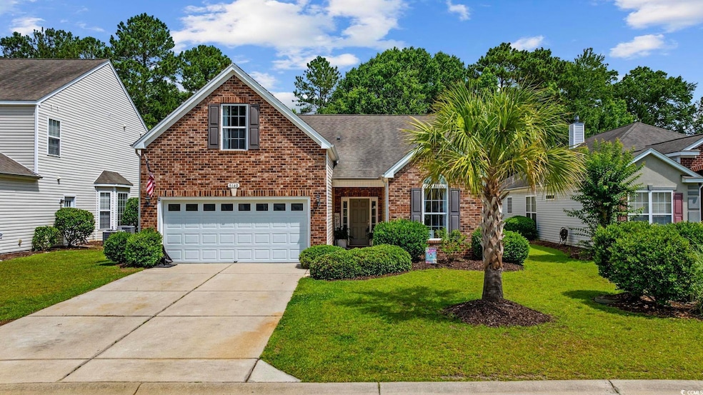Traditional home with brick siding, driveway, a front lawn, and a garage