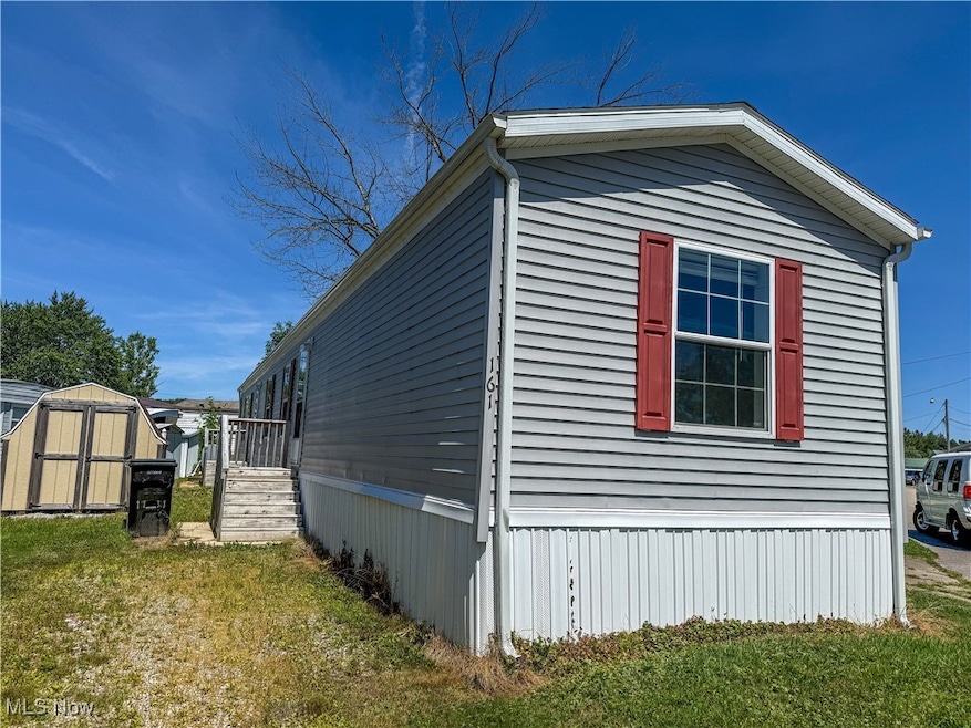 View of side of home with a shed and a yard
