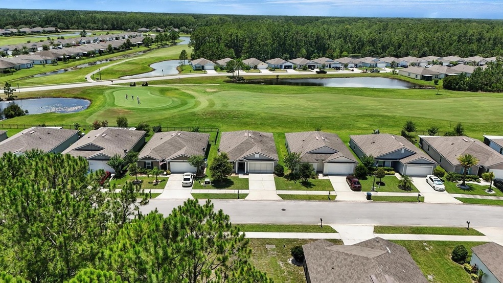 Aerial view of residential area featuring a golf course and a nearby body of water